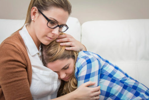 Mother embracing and soothes depressed daughter