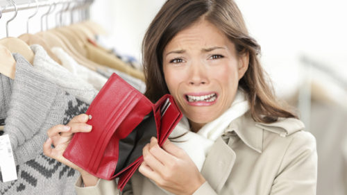 empty wallet - woman with no money in purse shopping. Female shopper in clothes store upset crying as she is out of money. Funny image of mixed race Caucasian / Asian woman.